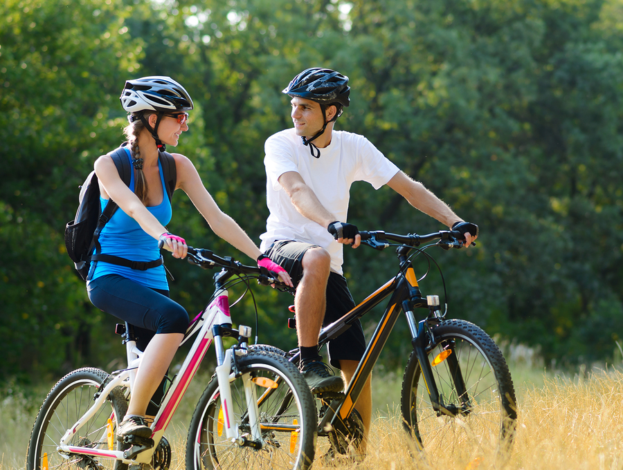 Young Happy Couple Riding Mountain Bikes Outdoor. Healthy Lifest