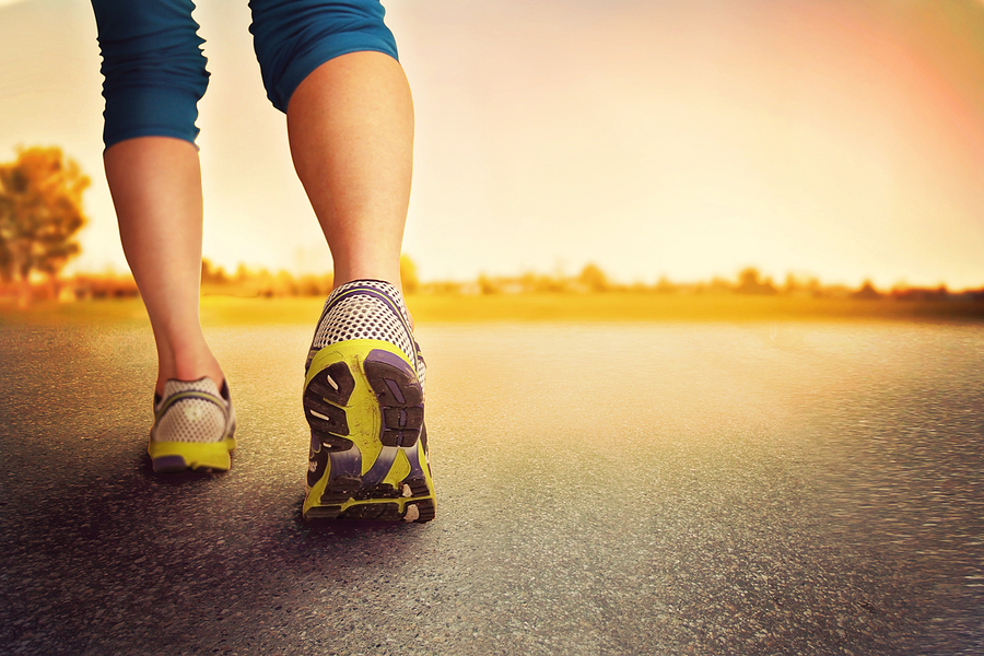 an athletic pair of legs on pavement during sunrise or sunset -